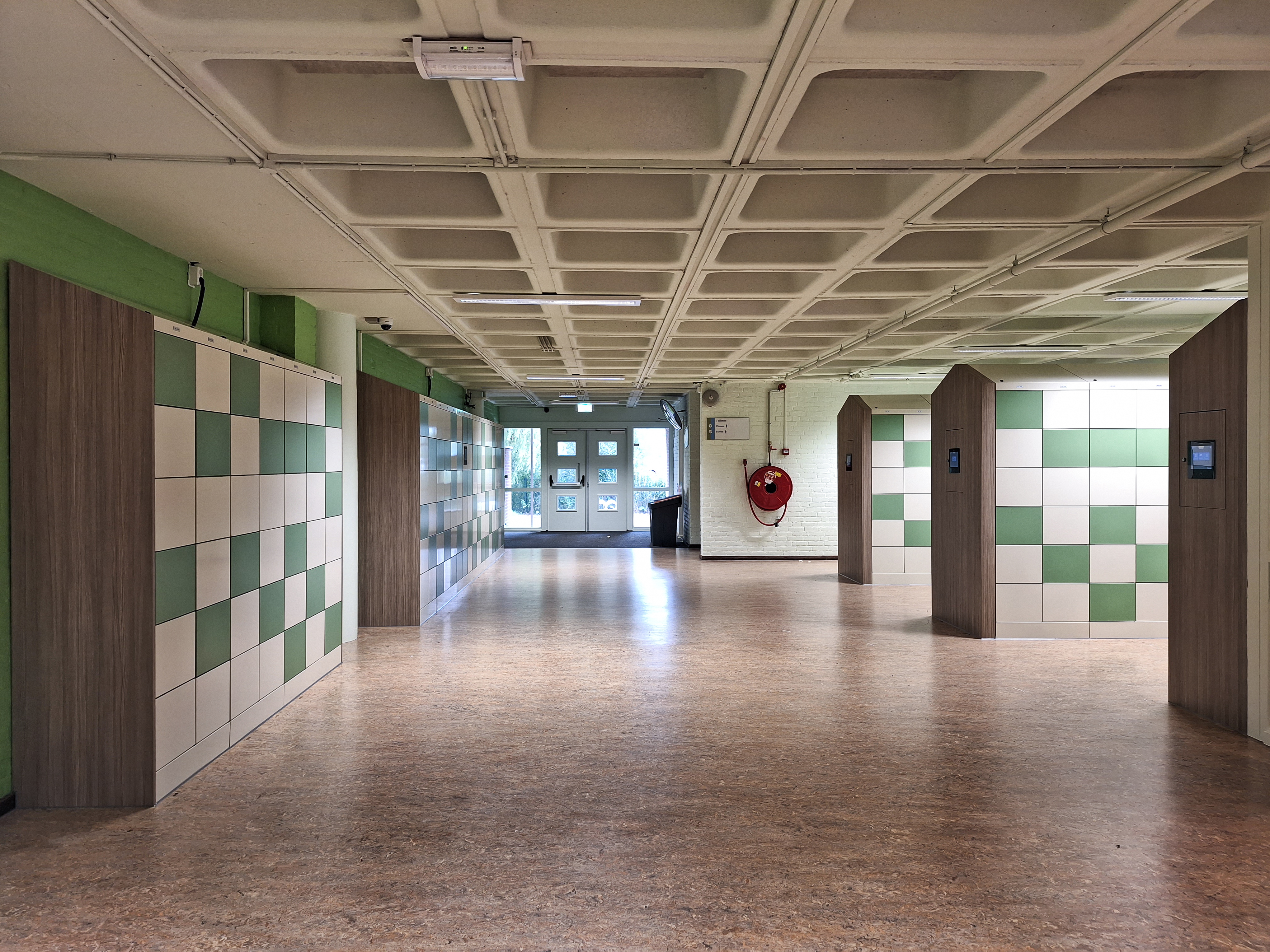 Couloir scolaire moderne avec casiers vert et blanc et parois en bois, offrant structure et tranquillit&eacute;